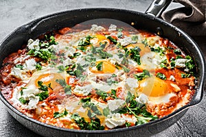 Homemade shakshuka, fried eggs, onion, bell pepper, tomatoes and parsley in a pan. Gray background. Top view