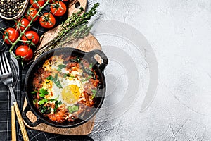 Homemade shakshuka, fried eggs, onion, bell pepper, tomatoes and parsley in a pan. Gray background. Top view. Copy space