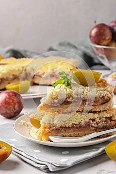 Homemade shortbread plum pie with cut pieces on plate on light gray background