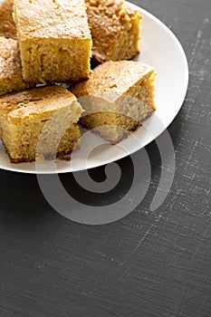 Homemade Sliced Cornbread Ready to Eat on a white plate on a black background, side view. Copy space
