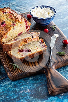 A homemade sliced cranberry and rosemary quick bread served with cream cheese.