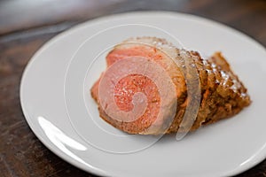 Homemade sliced grilled medium rare beef steak serving on white plate.