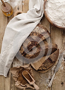 Homemade sliced round rye bread on a wooden table with malt and