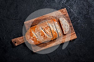 Homemade Sliced Wholemeal Multigrain Bread with Flax Seeds and Sesame on Wooden Board on Dark Table. Top View Flat Lay