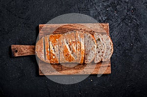 Homemade Sliced Wholemeal Multigrain Bread with Flax Seeds and Sesame on Wooden Board on Dark Table. Top View Flat Lay