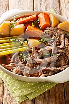 Homemade Slow Cooker Pot Roast with Carrots, Celery and Potatoes closeup on the wooden table. Vertical
