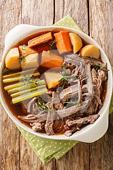 Homemade Slow Cooker Pot Roast with Carrots, Celery and Potatoes closeup on the wooden table. Vertical top view