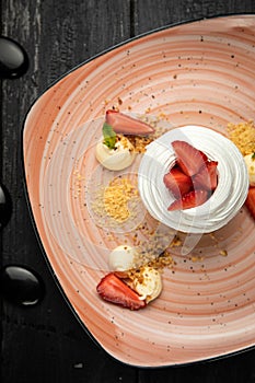 Homemade small strawberry pavlova meringue cakes with mascarpone cream and fresh mint leaves