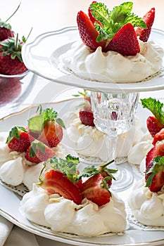 Homemade small strawberry pavlova meringue cakes with mascarpone cream and fresh mint leaves