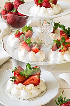 Homemade small strawberry pavlova meringue cakes with mascarpone cream and fresh mint leaves