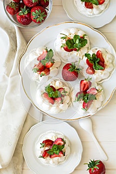 Homemade small strawberry pavlova meringue cakes with mascarpone cream and fresh mint leaves