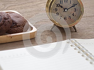 Homemade soft dark chocolate brownie cookies placed on a wooden plate on wooden table. Behind cookies have gold vintage alarm cloc