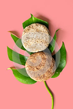 Homemade solid shampoo discs on red background close up green natural leaf, example of natural and eco friendly plastic free