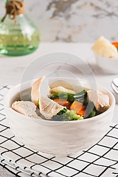 Homemade soup with chicken, cauliflower, broccoli, carrots and green beans in a bowl vertical view