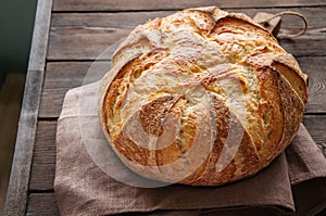 Homemade sourdough bread in a wooden tray on a wooden background