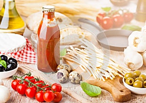 Homemade spaghetti pasta with quail eggs with bottle of tomato sauce and cheese on wooden background. Classic italian village food