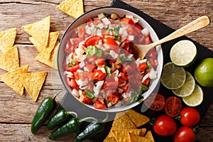 Homemade spicy pico de gallo close-up in a bowl and nachos. horizontal top view