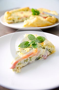 Homemade Spinach and Bacon Egg Quiche in a pie crust cut piece on plate. French cuisine