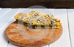 Homemade spinach french pie on a white wooden board