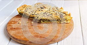 Homemade spinach french pie on a white wooden board