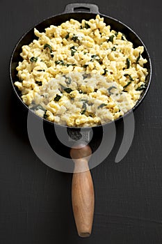 Homemade Spinach Mac and Cheese in a cast-iron pan on a black background, side view