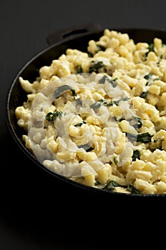 Homemade Spinach Mac and Cheese in a cast-iron pan on a black surface, side view. Close-up