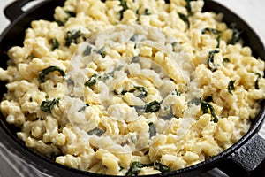 Homemade Spinach Mac and Cheese in a cast-iron pan on cloth, low angle view. Close-up