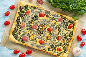 Homemade spinach puff pastry tart with cheese and tomatoes