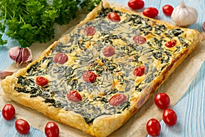 Homemade spinach puff pastry tart with cheese and tomatoes