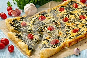 Homemade spinach puff pastry tart with cheese and tomatoes