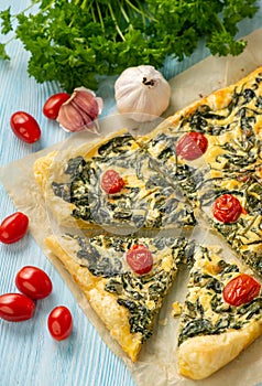 Homemade spinach puff pastry tart with cheese and tomatoes