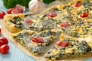 Homemade spinach puff pastry tart with cheese and tomatoes