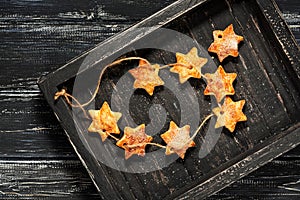 Homemade star cookies on a black wooden tray. Christmas background with cookies.