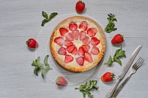 Homemade strawberry cheesecake on the gray background with many fresh strawberries, mint leaves, vintage silver knife and fork. De