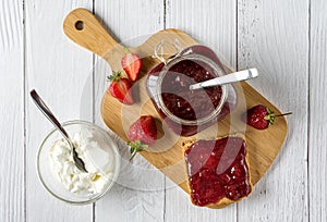 Homemade strawberry jam in a glass jar with Creme Fraiche