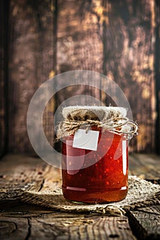 Homemade strawberry jam in a glass jar, tied with rustic burlap