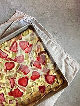 Homemade strawberry-rhubarb clafoutis dessert in square aluminum pan