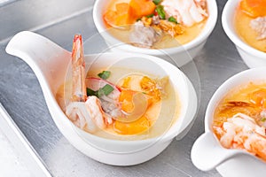 Homemade style steamed egg with shrimp and vegetables in a ceramic bowl on wooden table. healthy food concept