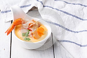 Homemade style steamed egg with shrimp and vegetables in a ceramic bowl on wooden table. healthy food concept