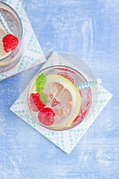 Homemade summer cold raspberry lemon cocktail with sparkling water and crushed iced in glasses