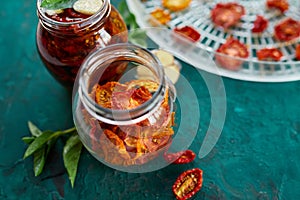 Homemade sun dried tomatoes with herbs, garlic in olive oil in a glass jar