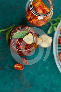 Homemade sun dried tomatoes with herbs, garlic in olive oil in a glass jar