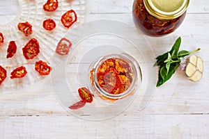 Homemade sun dried tomatoes with herbs, garlic in olive oil in a glass jar