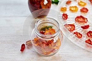 Homemade sun dried tomatoes with herbs, garlic in olive oil in a glass jar