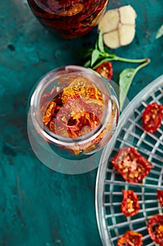 Homemade sun dried tomatoes with herbs, garlic in olive oil in a glass jar