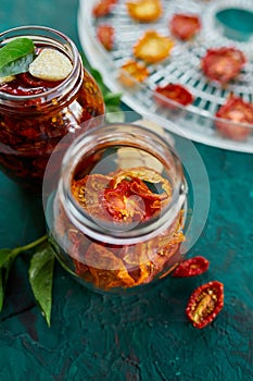 Homemade sun dried tomatoes with herbs, garlic in olive oil in a glass jar