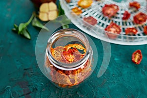 Homemade sun dried tomatoes with herbs, garlic in olive oil in a glass jar