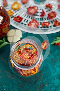 Homemade sun dried tomatoes with herbs, garlic in olive oil in a glass jar