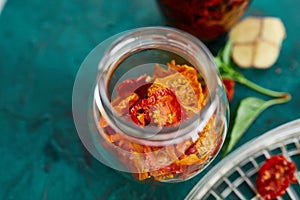 Homemade sun dried tomatoes with herbs, garlic in olive oil in a glass jar