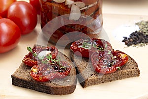 Homemade sun-dried tomatoes with olive oil in a glass jar. Sandwich with black bread and sun-dried tomatoes
